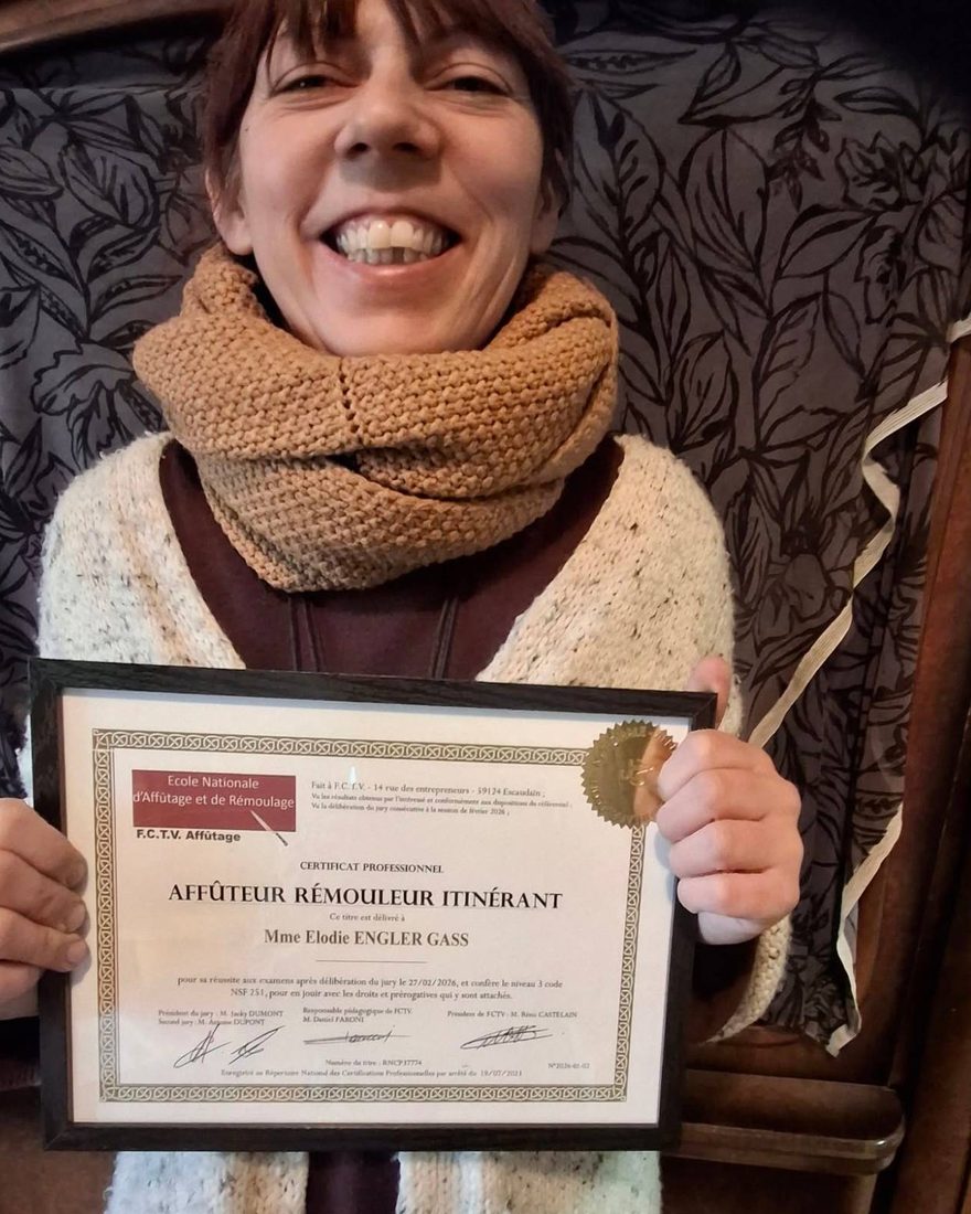 Elodie, souriante, tient son certificat professionnel d'Affûteur Rémouleur Itinérant encadré